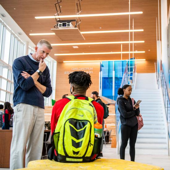 Instructor talking with a student in the nursing and human performance building.